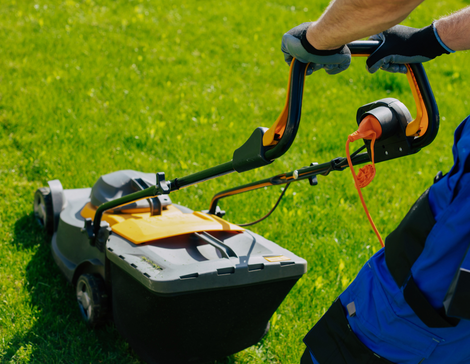 Person pushing a lawn mower across the grass.