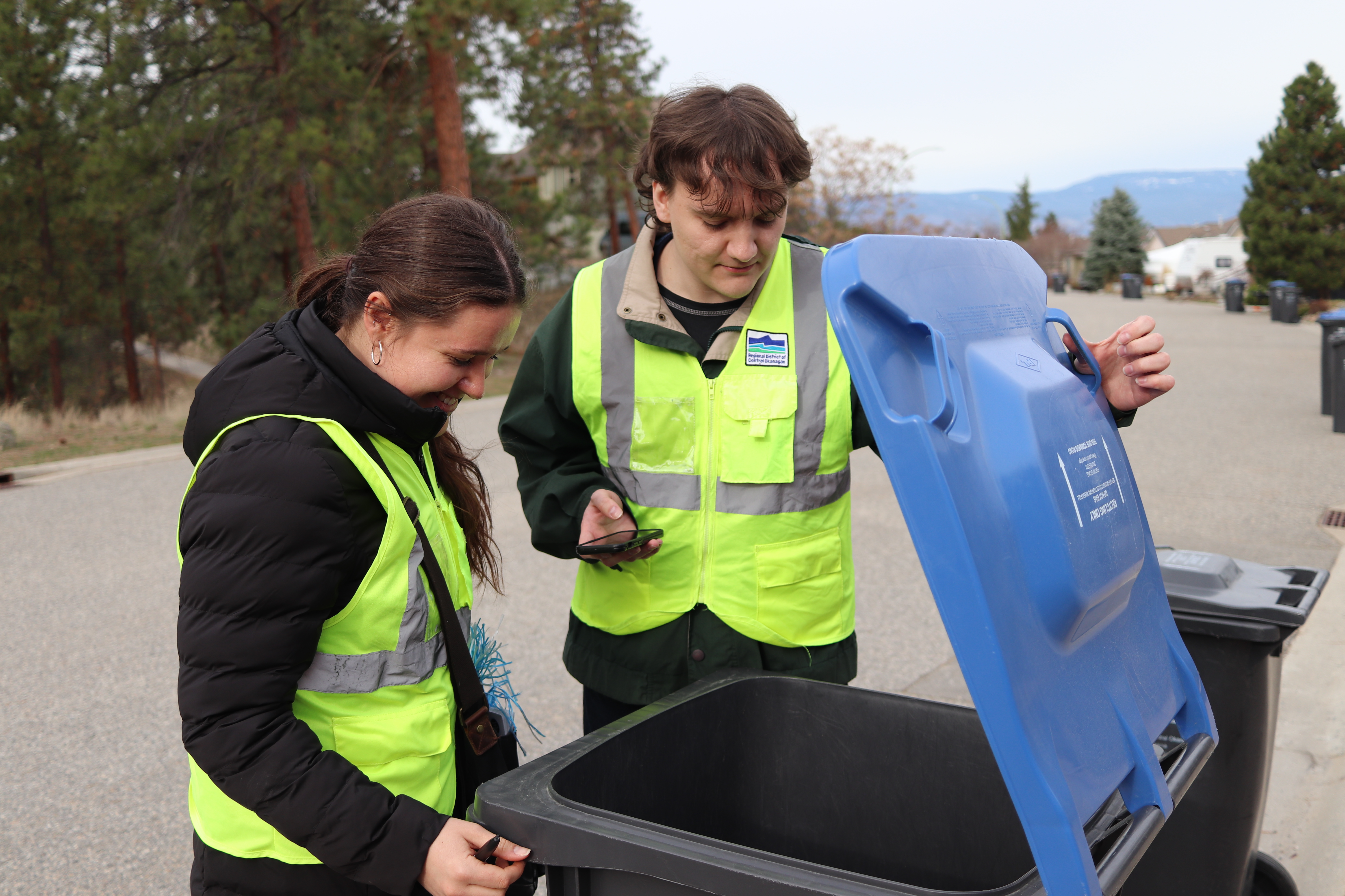 Recycling ambassadors looking inside of a curbside recycling cart.