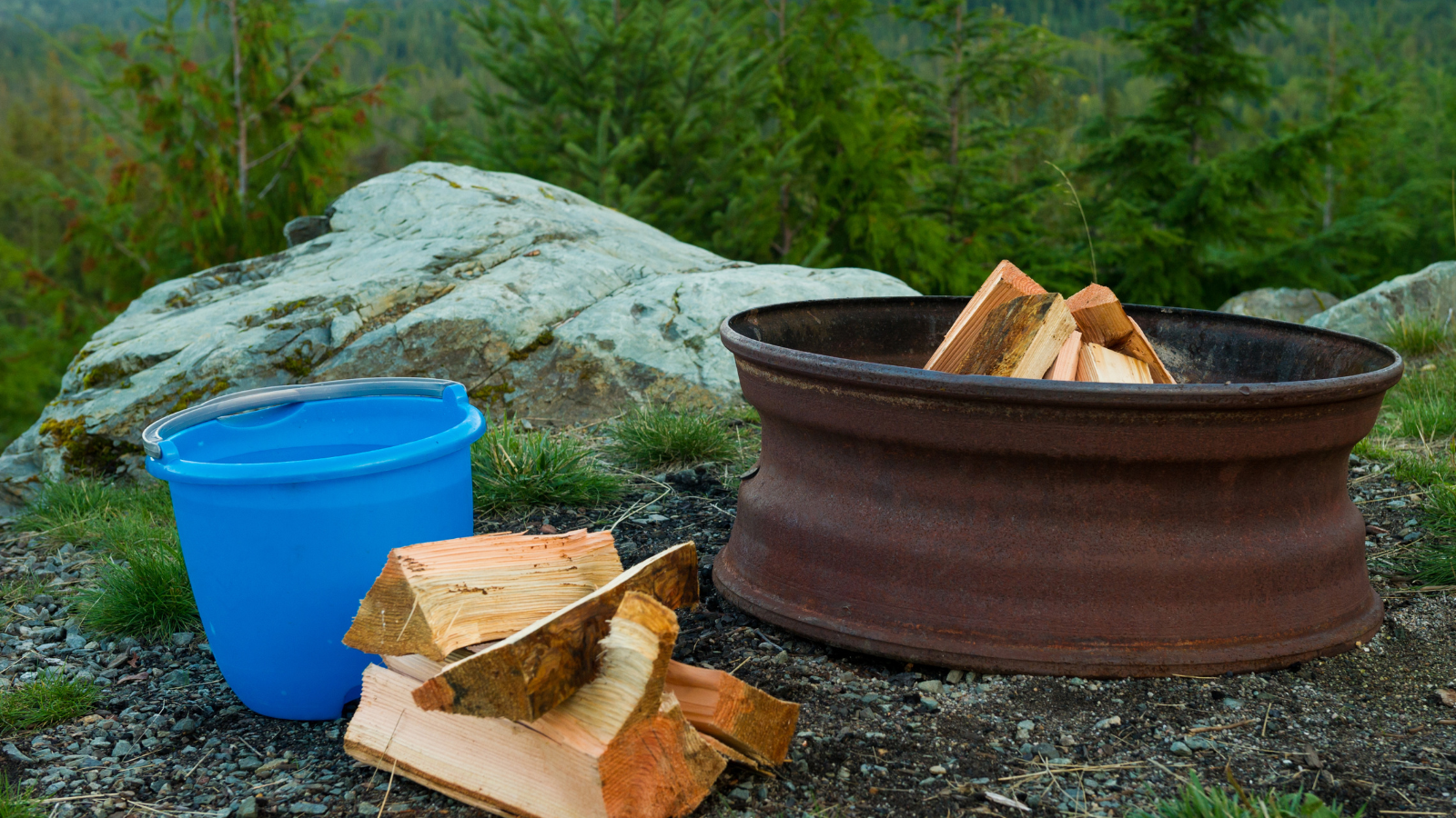 Campfire setup with a bucket of water nearby for safety.