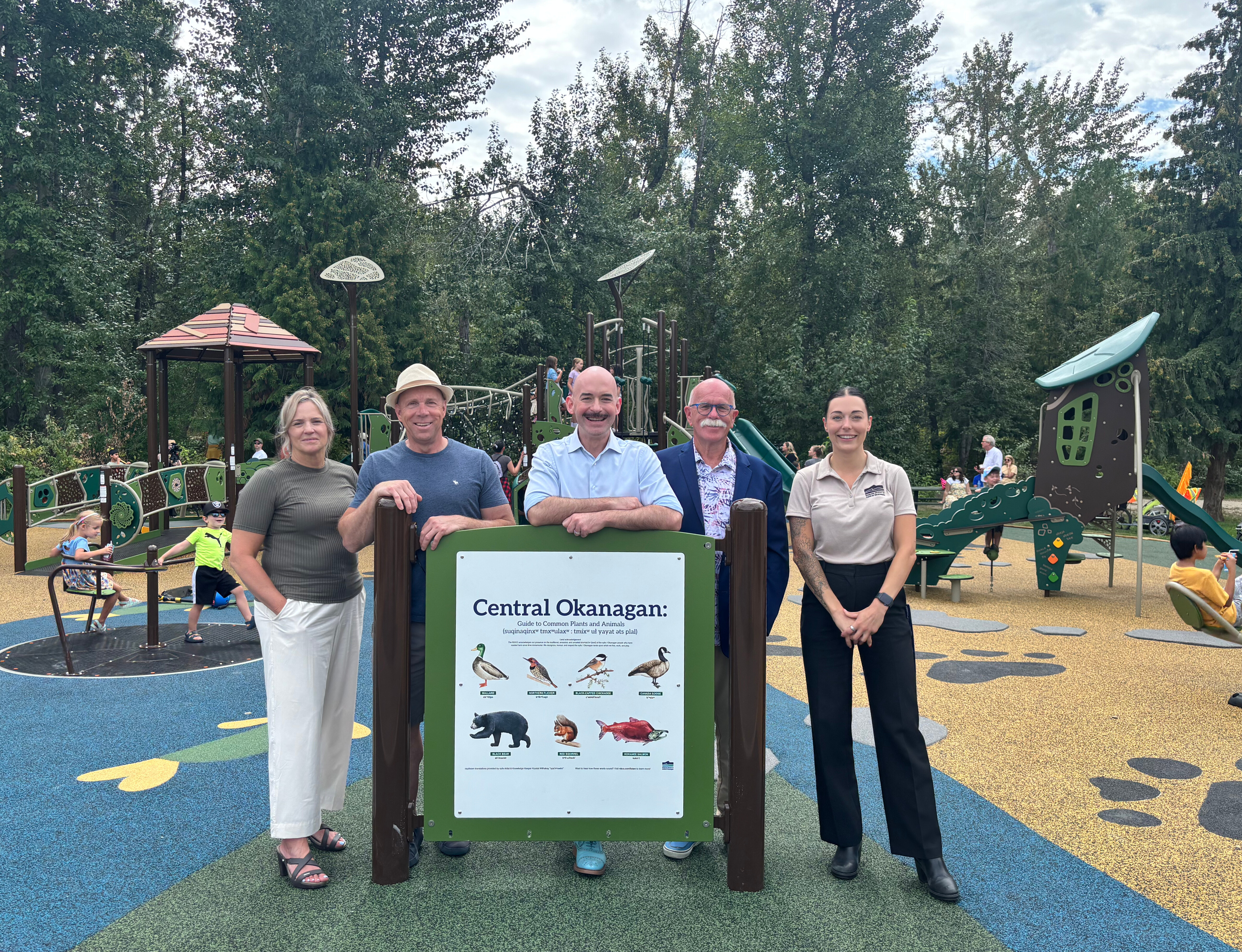 Group photo at the opening of the new Mission Creek playground. CAO Sally Ginter, Director Ron Cannan, Chair Loyal Wooldridge, Vice Chair Blair Ireland, and RDCO Parks staff member Tamara Oljaca stand together in front of the newly installed playground equipment. 
