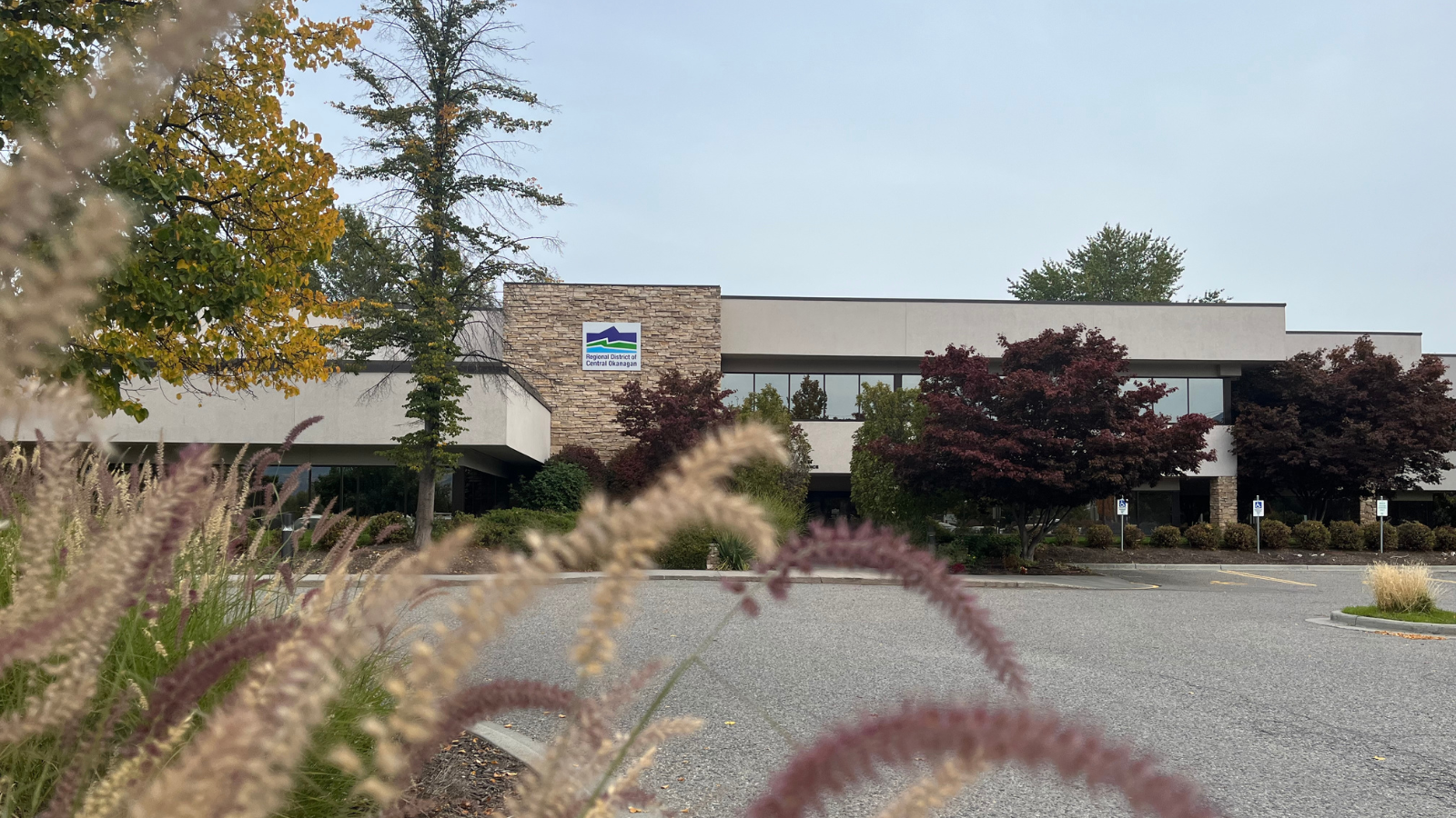 Exterior view of the Regional District of Central Okanagan office building at 1450 KLO Road, surrounded by trees and landscaping.