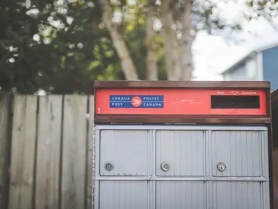Canada Post community mailbox with multiple locked compartments and a red panel for outgoing mail.